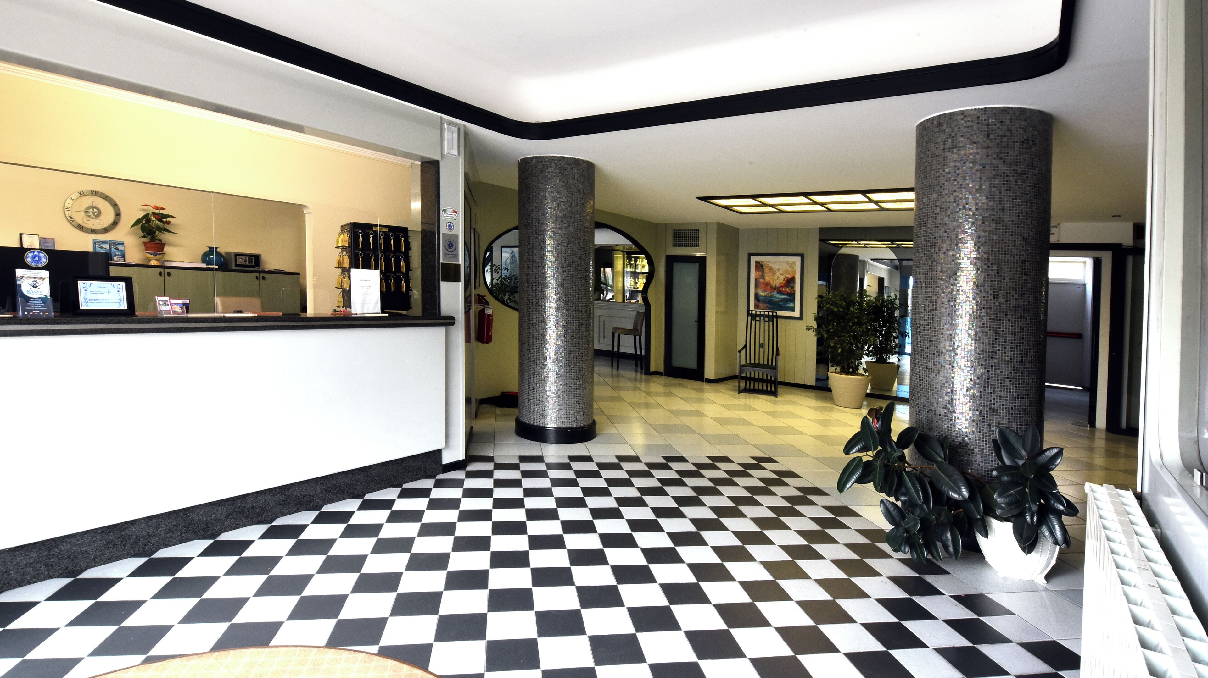 A lobby with a checkered floor, a reception desk, and decorative pillars.