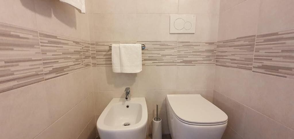A bathroom with a bidet, toilet, and a towel hanging on the wall.