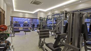 Une salle de sport équipée de tapis de course, d’appareils de musculation et dotée d’une grande fenêtre.