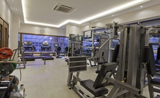 Un gimnasio con cintas de correr, máquinas de pesas y un ventanal grande.