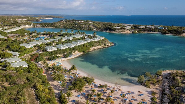 A coastal resort with beachfront villas, a sandy beach, and clear turquoise waters.