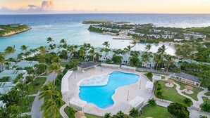 Un resort con una piscina grande rodeada de palmeras y vistas al océano.