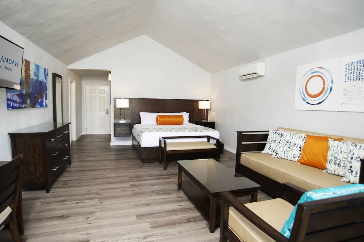 A hotel room with a bed, a sofa, a desk, and a dresser.
