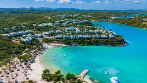 An aerial view of a resort with multiple buildings, a beach, and clear turquoise waters.