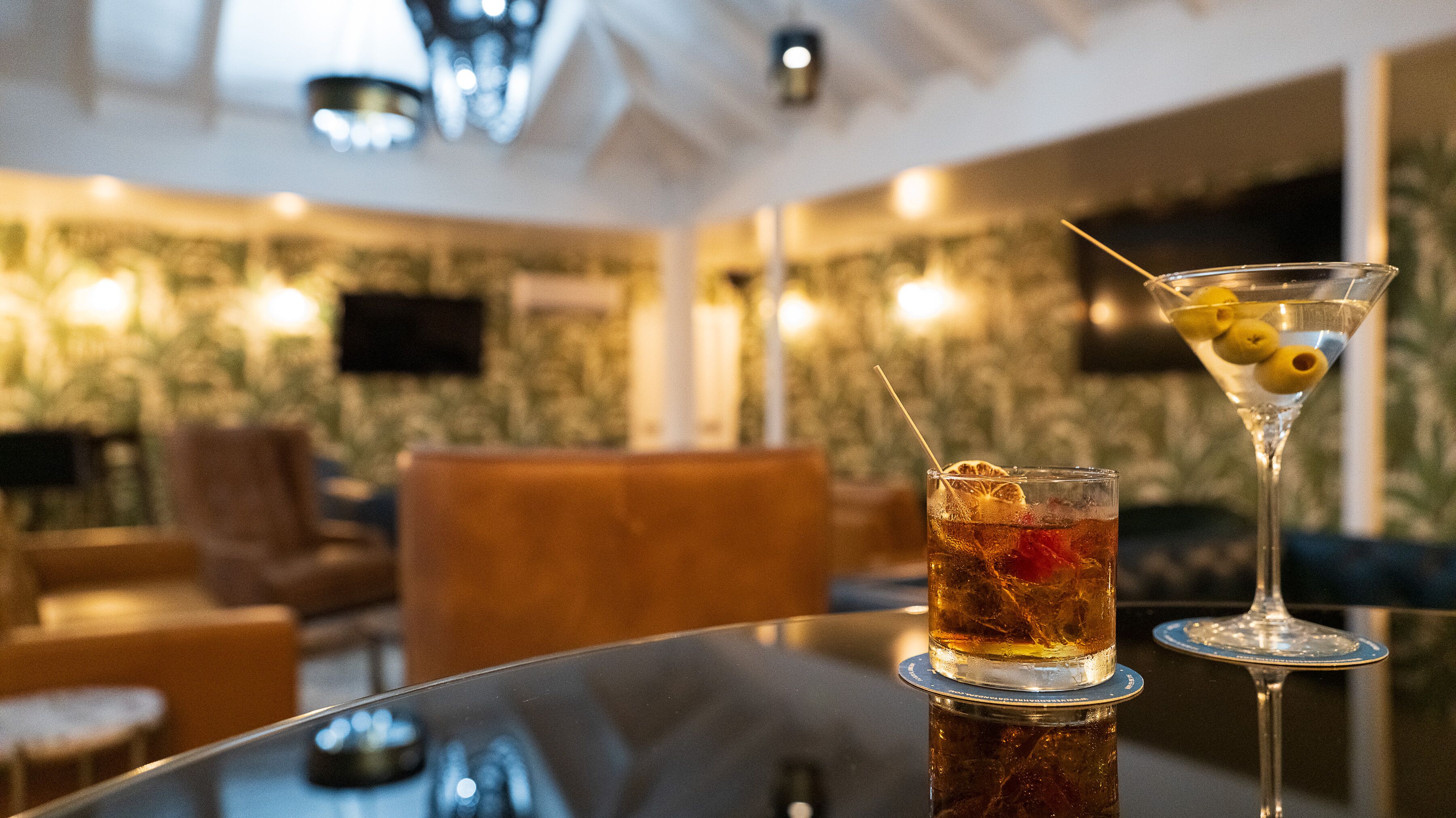 Een bar met een glas ijsthee en een martini op een glazen tafel.