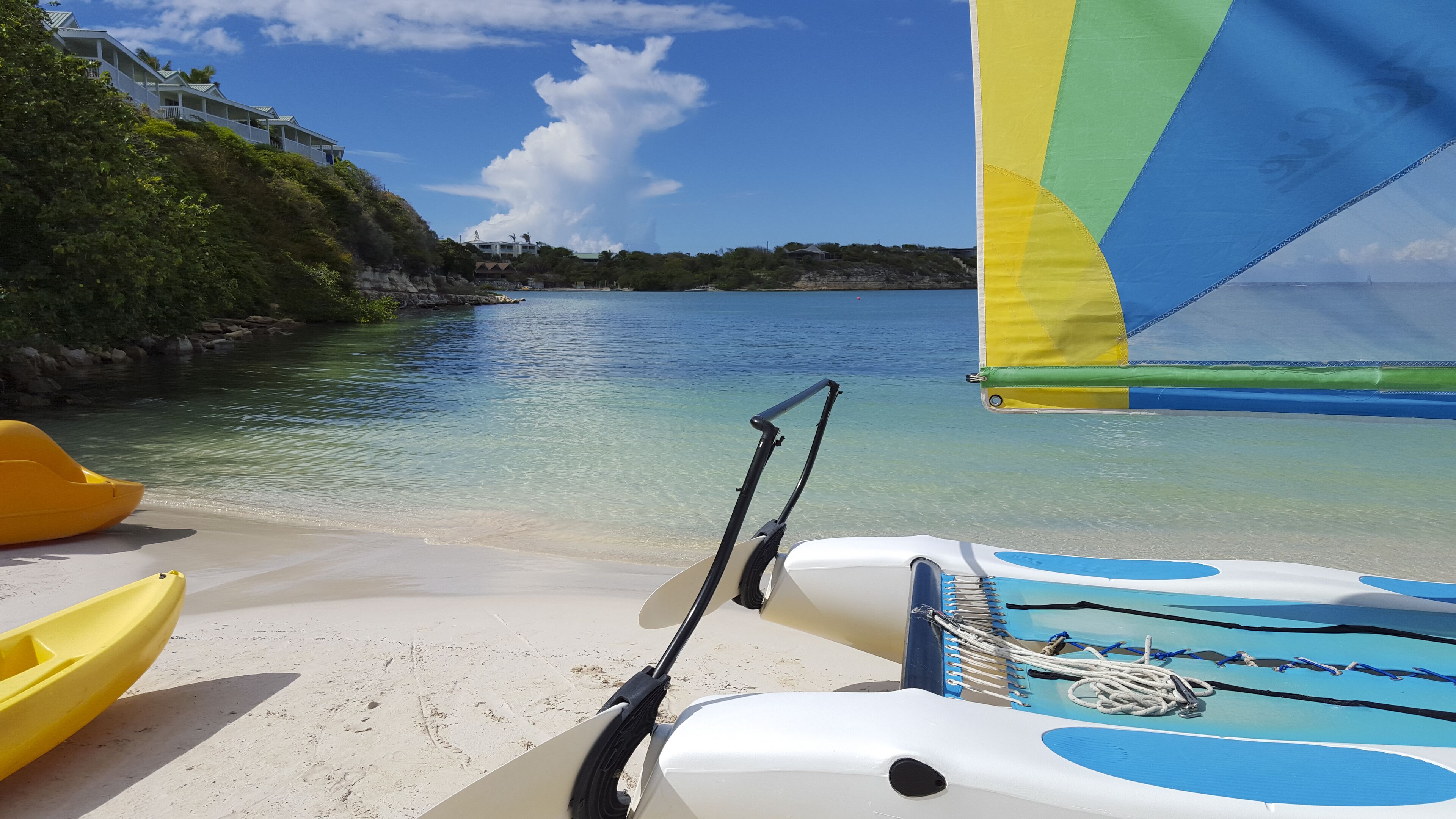 A beach with a sailboat and kayaks.