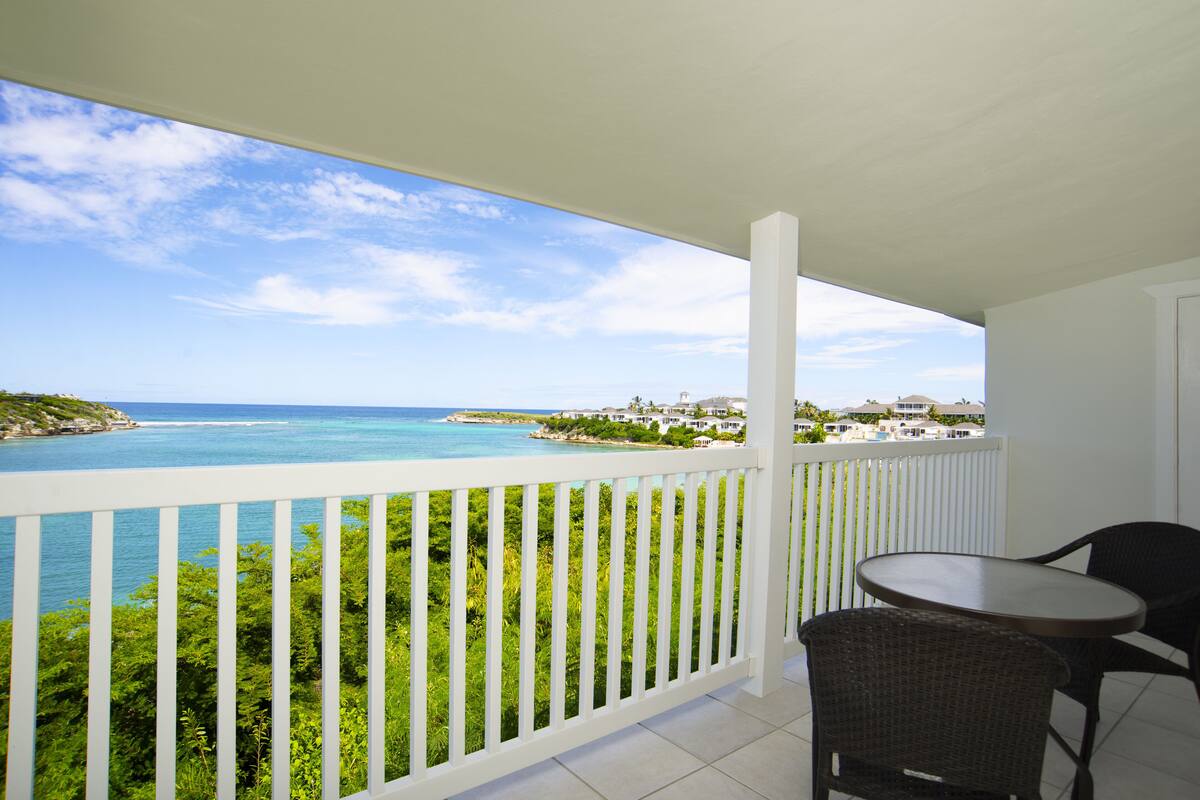 A balcony with a white railing overlooking a coastal view.