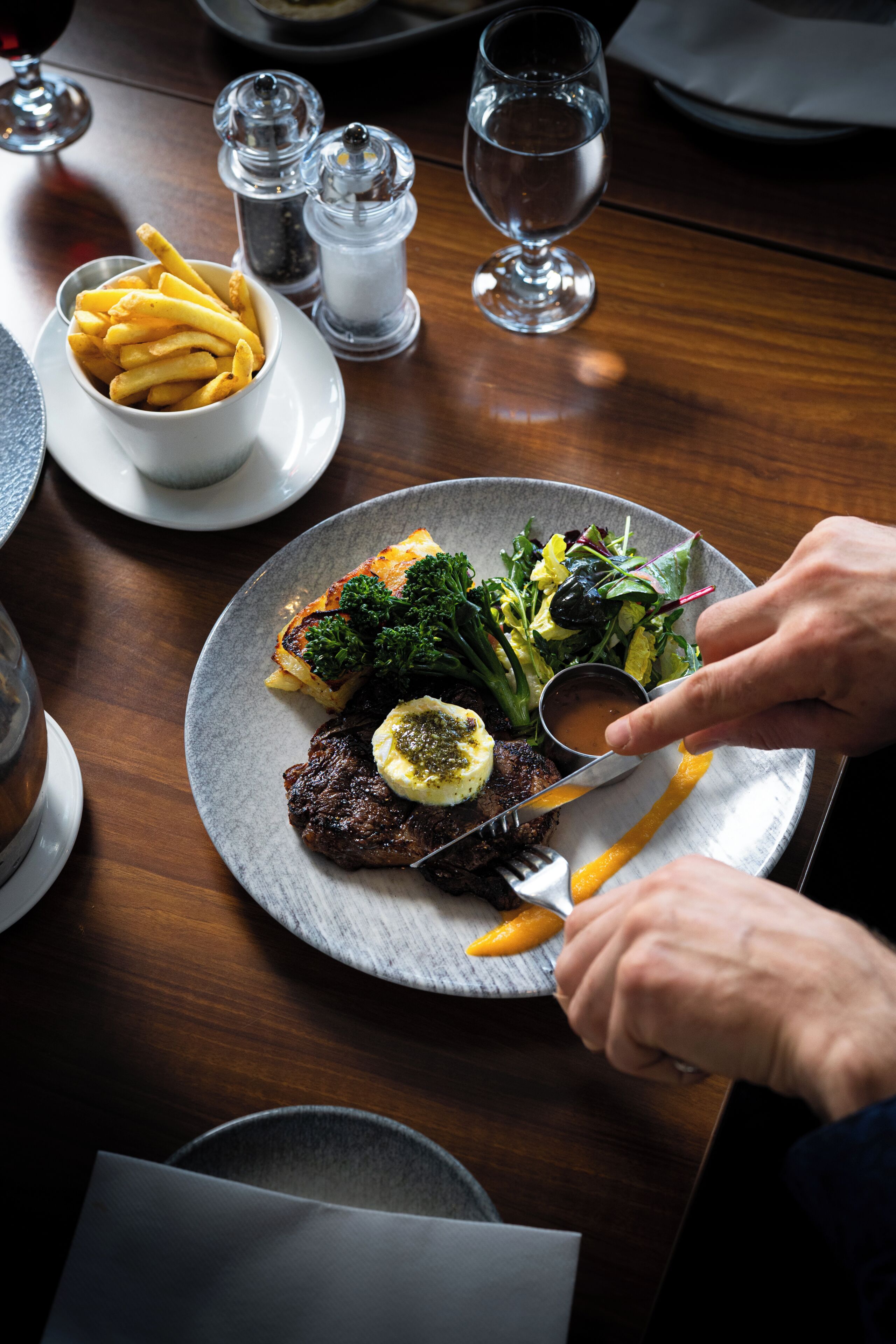 A dining table with a plate of food, a glass of water, and salt and pepper shakers.