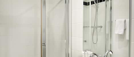 A modern bathroom with a glass-enclosed shower, a white sink, and a large mirror.