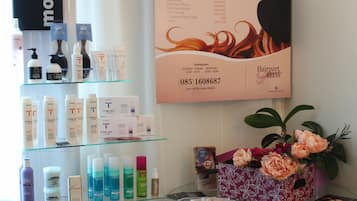 Ein Friseursalon mit verschiedenen Haarpflegeprodukten auf Regalen und einem Plakat, das Dienstleistungen bewirbt.