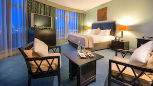 A hotel room with a bed, two chairs, a desk with a lamp, a TV, and a minibar. - Cork International Hotel (Cork)
