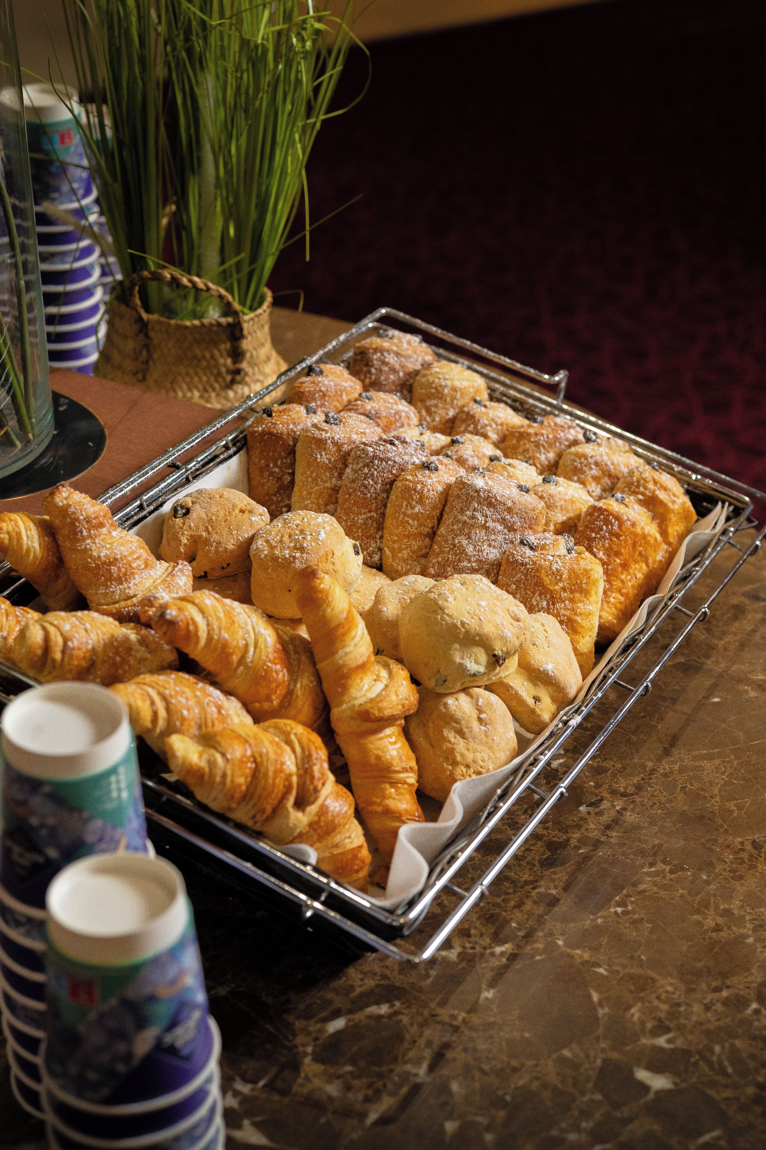 A tray of assorted pastries and a stack of disposable cups.