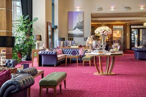 Experience the elegant lobby with plush seating, a central coffee table, and a stunning lighthouse painting.