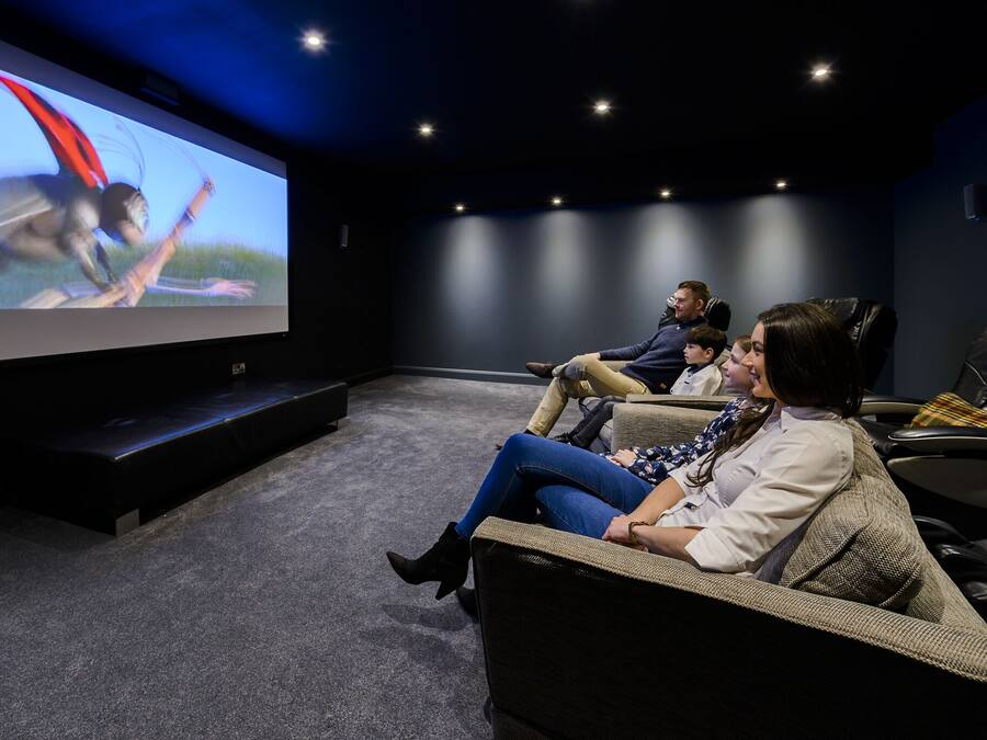 A movie theater with a large screen, comfortable seating, and a dark interior.