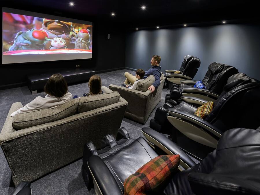 Un cine en casa con sillones reclinables y una pantalla grande.