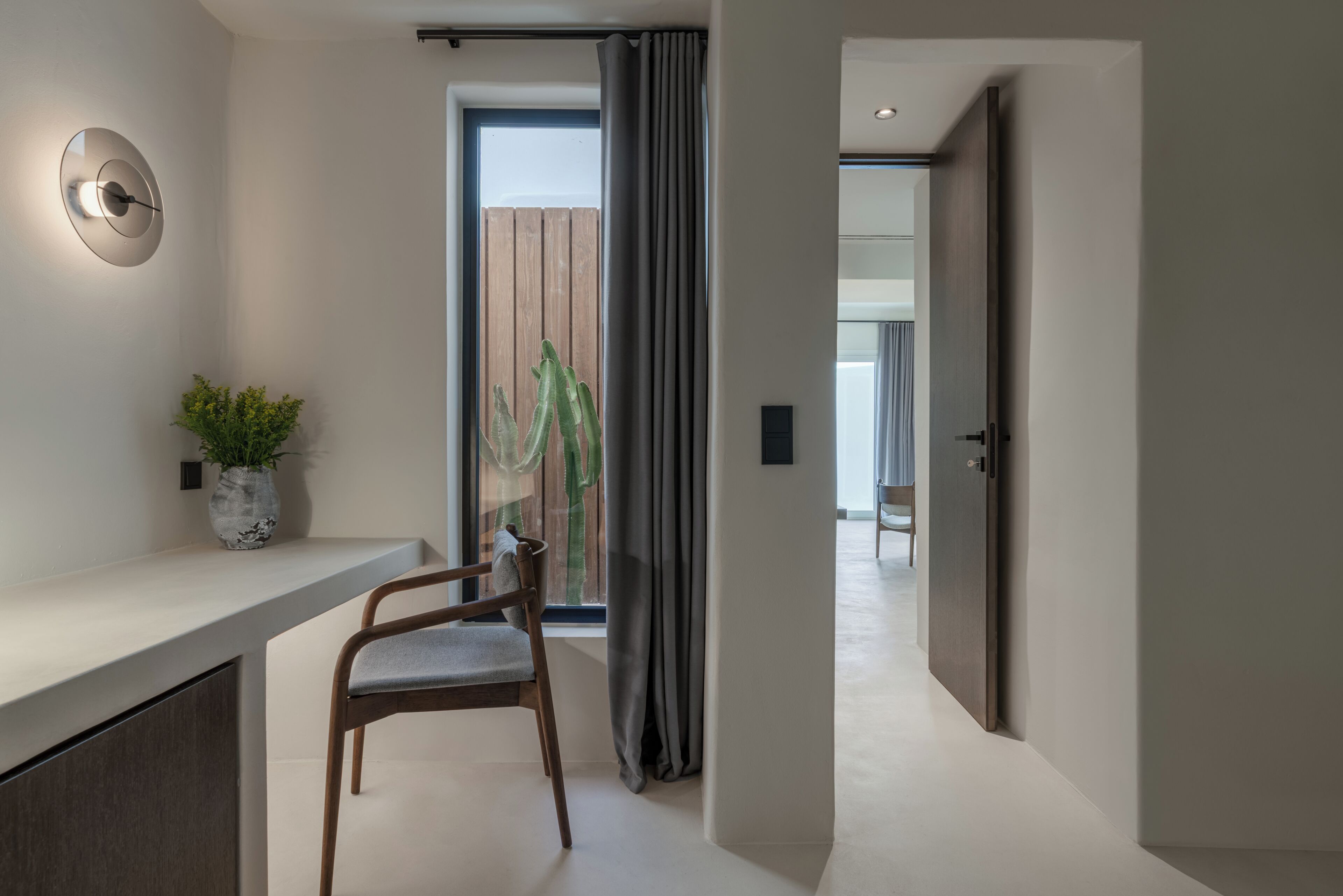 Un intérieur moderne au design minimaliste, comprenant une chaise en bois, un comptoir blanc et une plante en pot.