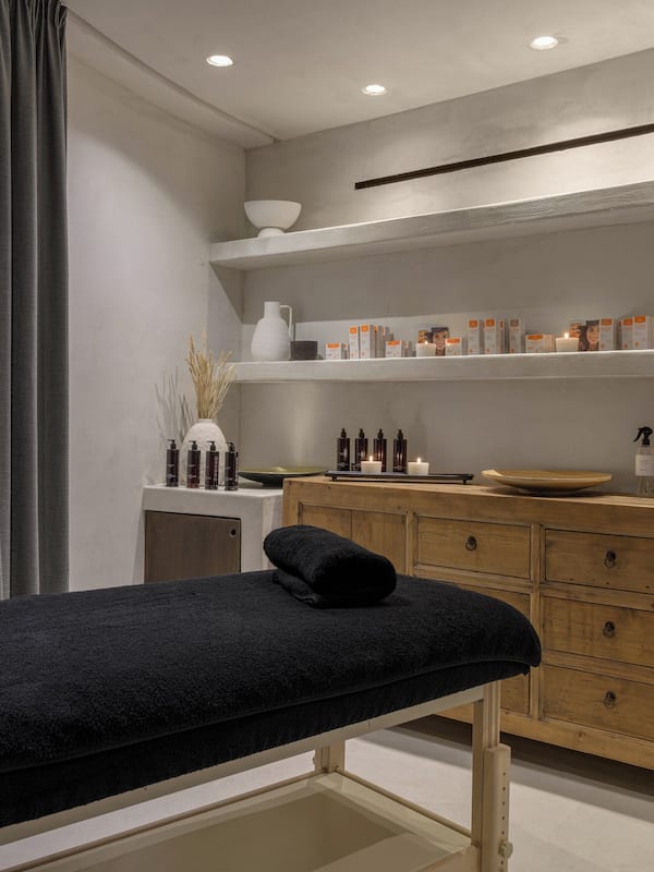 Experience relaxation in this serene spa room, featuring a massage table, storage cabinet, and soothing ambiance.