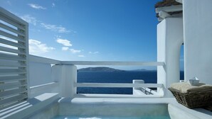 Een balkon met uitzicht op zee, een jacuzzi en een rieten mand.