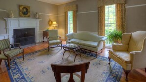 A traditional living room with a fireplace, a sofa, armchairs, and a coffee table. - Oak Grove Bed and Breakfast (South Boston)