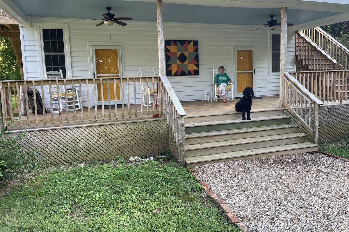 A house with a porch, a staircase, and a dog.