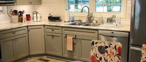 A kitchen with a dining table, chairs, a refrigerator, a sink, and a window.