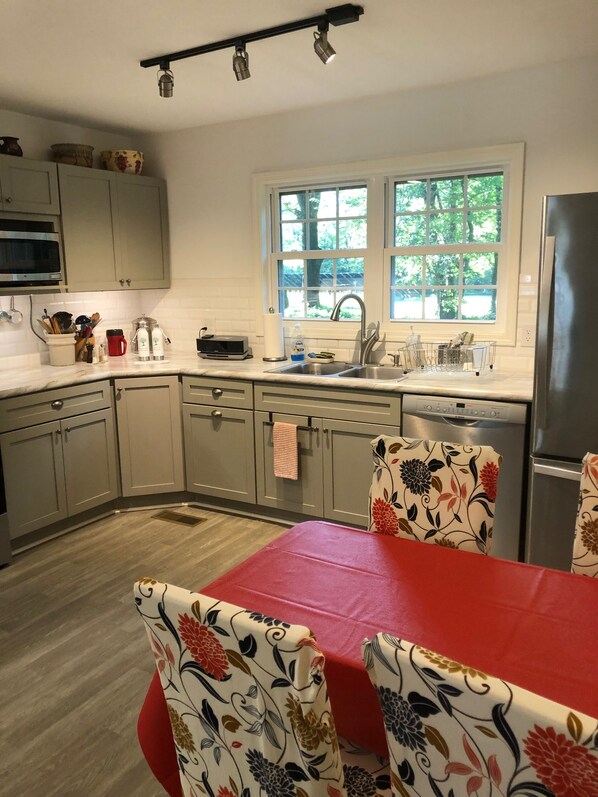 Una cocina con mesa, sillas, refrigerador, pileta y ventana.