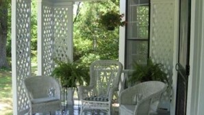 A covered porch with wicker furniture and potted plants. - Oak Grove Bed and Breakfast (South Boston)