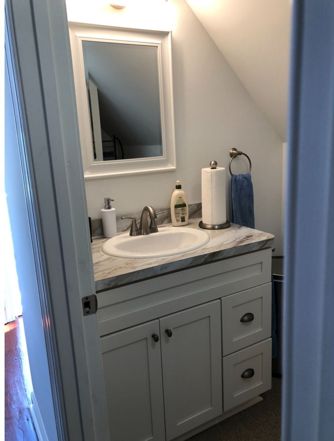 Une salle de bain avec un meuble-lavabo blanc, un évier, un miroir et un porte-serviettes.