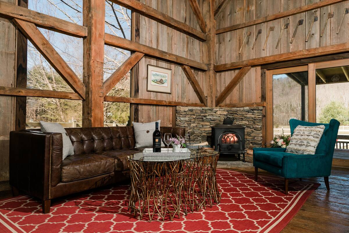 Un interior rústico con chimenea de piedra, sofá de cuero y un sillón color turquesa.