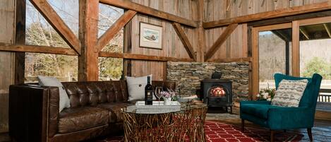 A rustic interior with a stone fireplace, leather sofa, and a teal armchair.