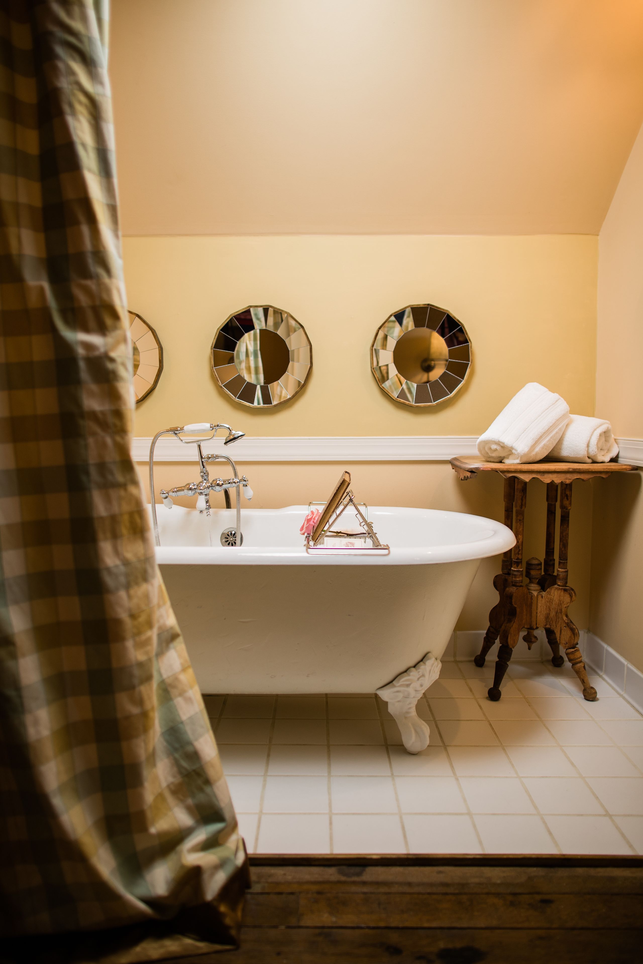 Ein Badezimmer mit einer Badewanne auf Füßen, einem Waschbecken und zwei Spiegeln an der Wand.