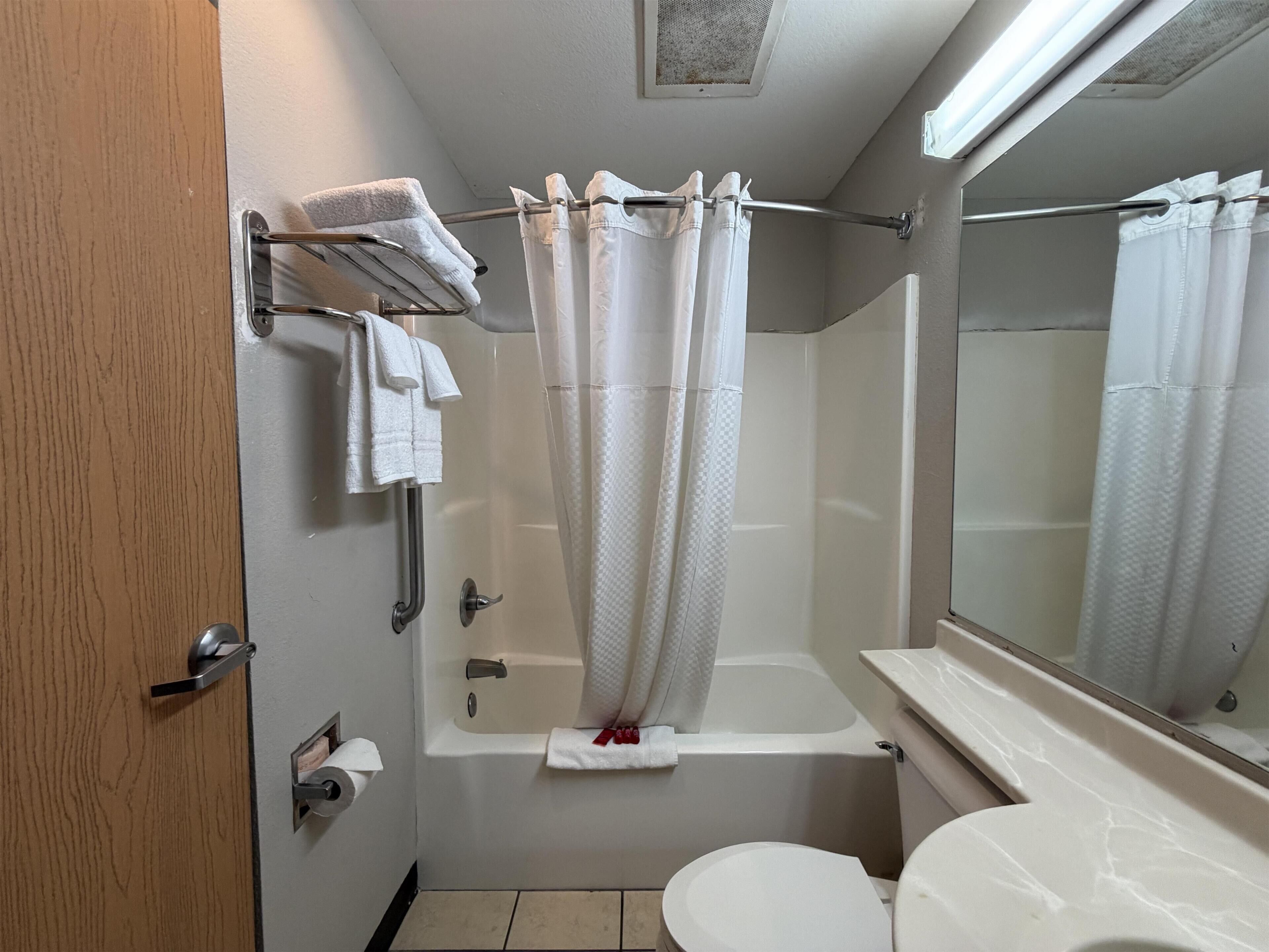 A bathroom with a bathtub, toilet, and a shower curtain.