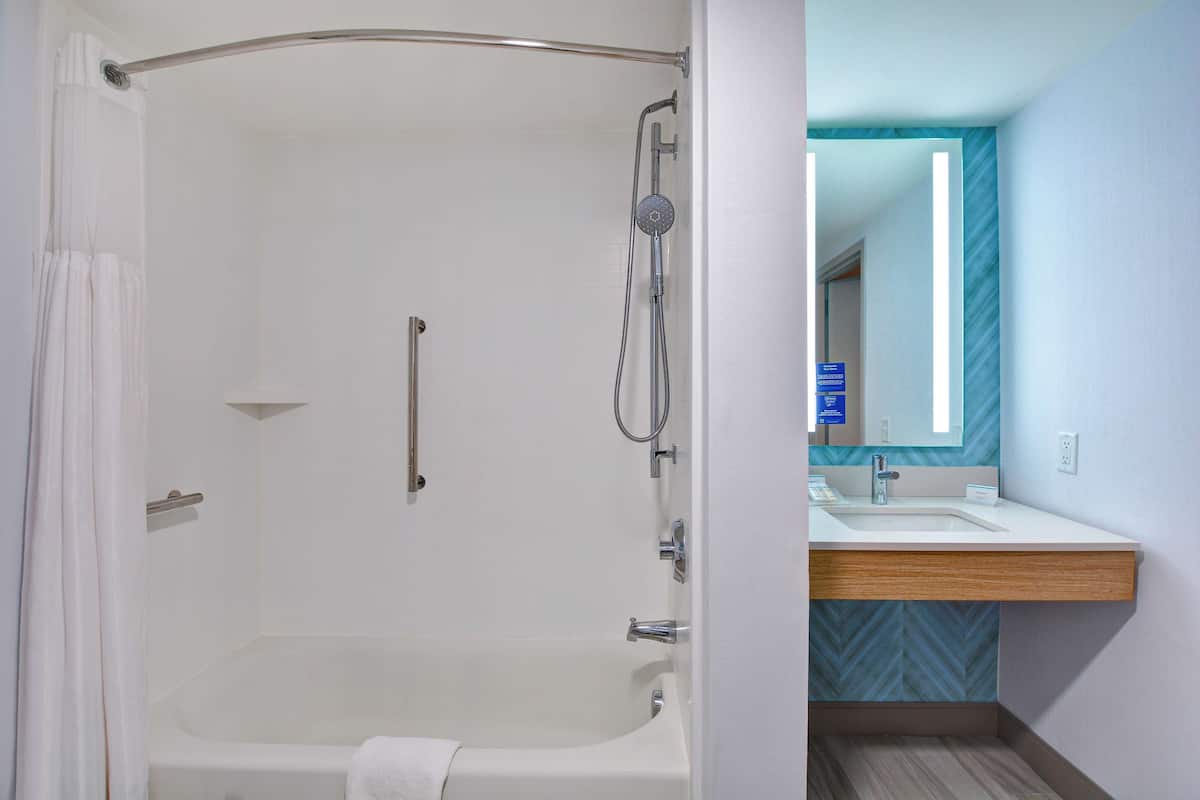 A modern bathroom with a walk-in shower, a bathtub, and a vanity with a mirror.