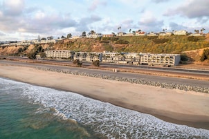 Un hotel frente al mar con varias construcciones, una playa y una carretera.