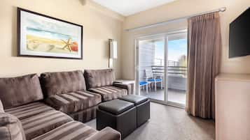 Een moderne woonkamer met een grote hoekbank, een flatscreen-tv en een balkon met uitzicht.