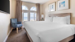 Una habitación de hotel con una cama grande, una silla, un televisor y una ventana con cortinas.