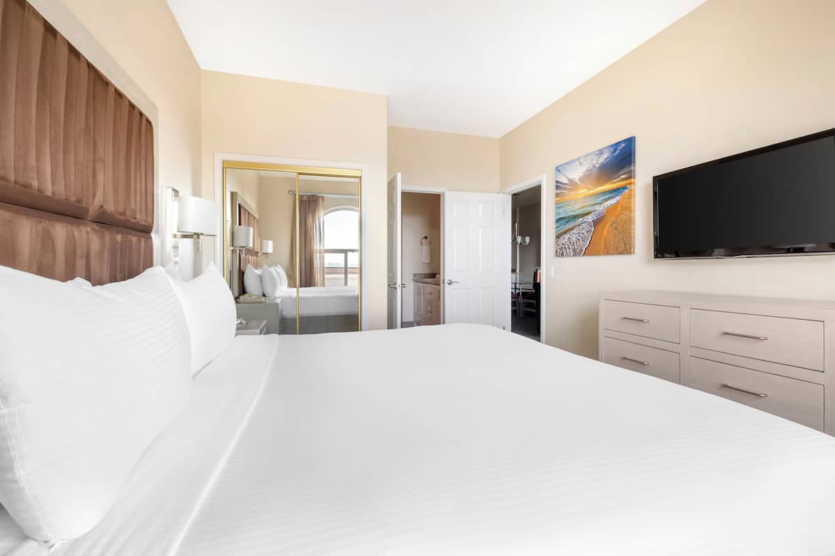 Ein Hotelzimmer mit einem großen Bett, einem Flachbildfernseher, einem Gemälde und einem Kleiderschrank.