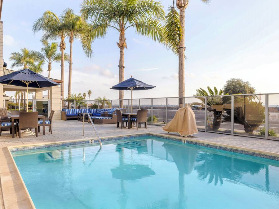 A swimming pool with lounge chairs and umbrellas, surrounded by palm trees.