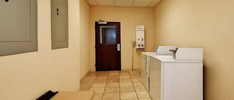 A laundry room with a washing machine, a bench, and a door leading to another room.