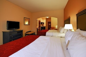 Una habitación de hotel con dos camas, televisión, escritorio y lámpara.