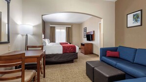 Ein Hotelzimmer mit Bett, Schreibtisch, Stuhl, Sofa, Fernseher und einem Bild an der Wand.