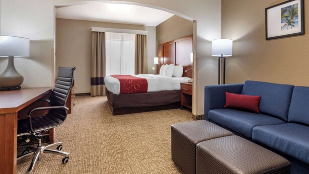 Ein Hotelzimmer mit einem Bett, einem Schreibtisch mit Stuhl, einer Couch und einem kleinen Hocker.