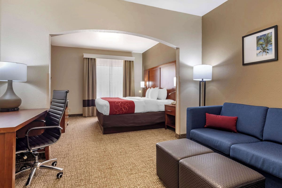 Une chambre d’hôtel comprenant un lit, un bureau avec une chaise, un canapé et un petit pouf.