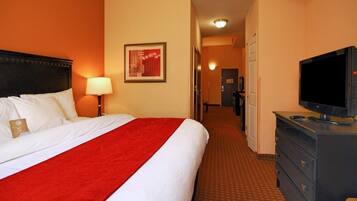 Une chambre d’hôtel comprenant un lit, une télévision, une commode et un couloir menant à une porte.