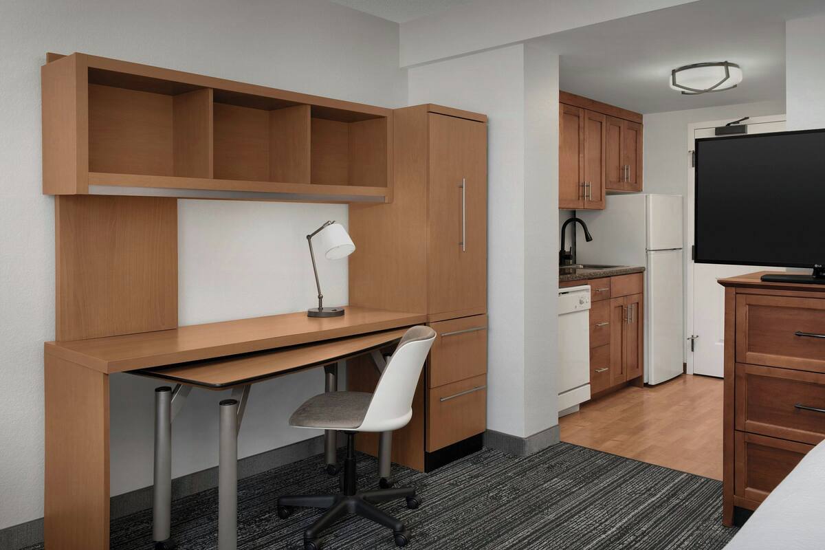 A compact kitchenette with a refrigerator, sink, and cabinets.