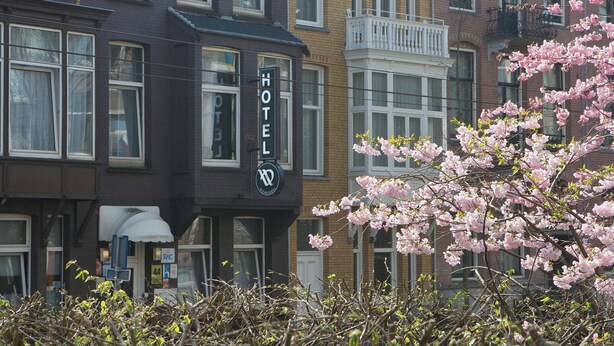 Een hotel met een opvallend 'HOTEL' bord, meerdere ramen en een balkon.