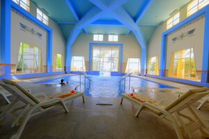 Una piscina al aire libre, sombrillas, sillones reclinables de piscina