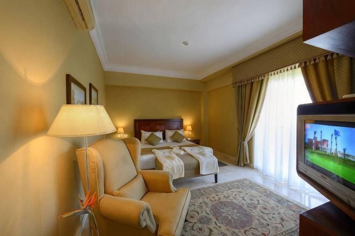 Une chambre d’hôtel avec un lit, un canapé, une télévision et une lampe.