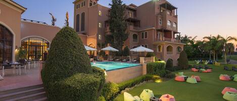 Um resort com piscina, área de estar externa e um gramado bem cuidado.