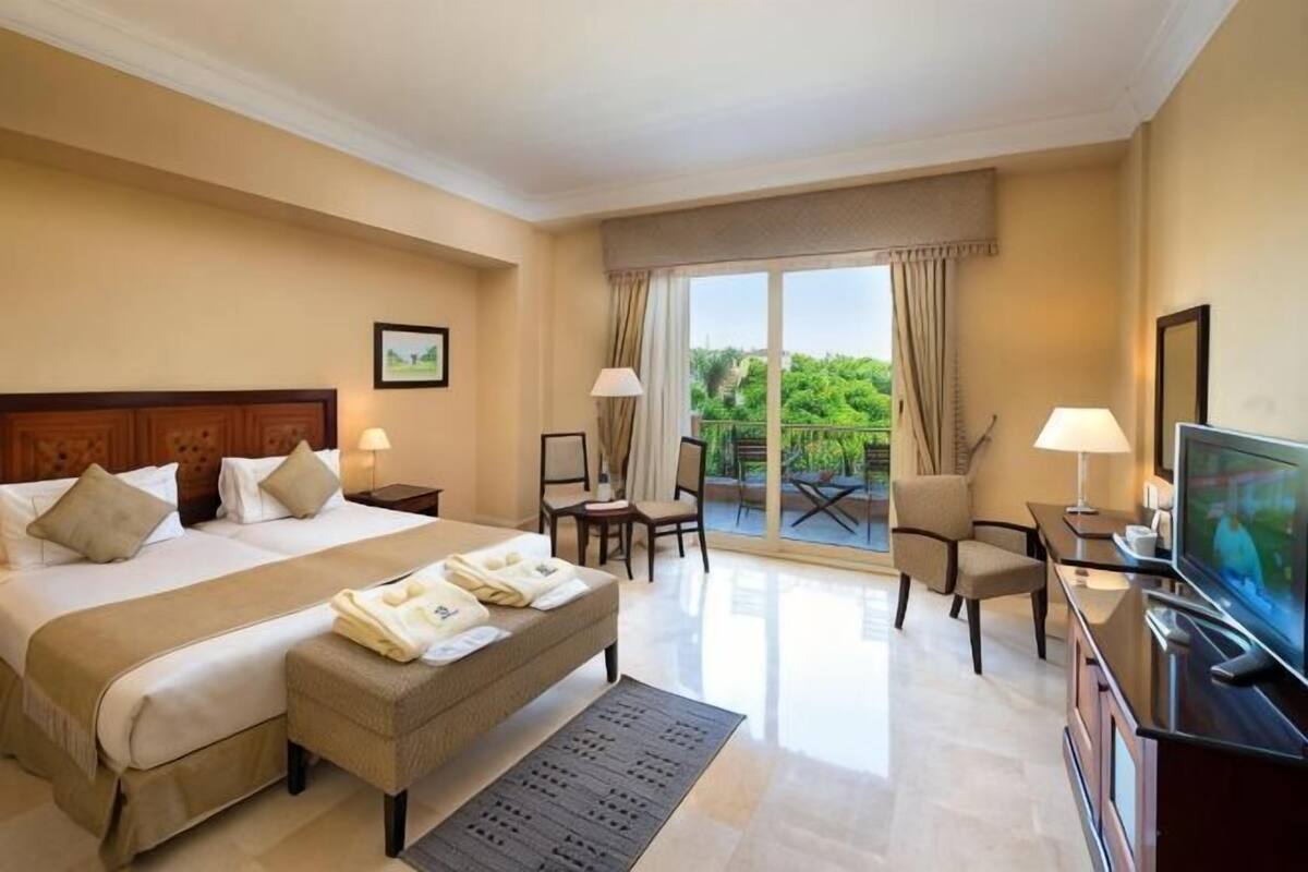 Une chambre d’hôtel avec un grand lit, une télévision, un bureau et un balcon avec vue.